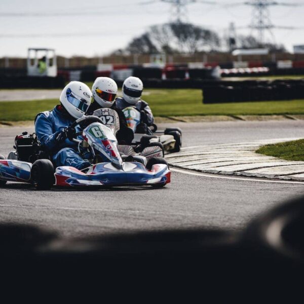 Two go-karts racing on a track in Twente, outdoor and indoor settings visible