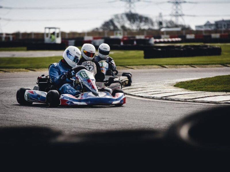 Two go-karts racing on a track in Twente, outdoor and indoor settings visible