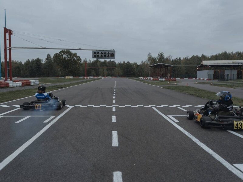 Person racing a go-kart indoors, cornering at speed with focus and determination