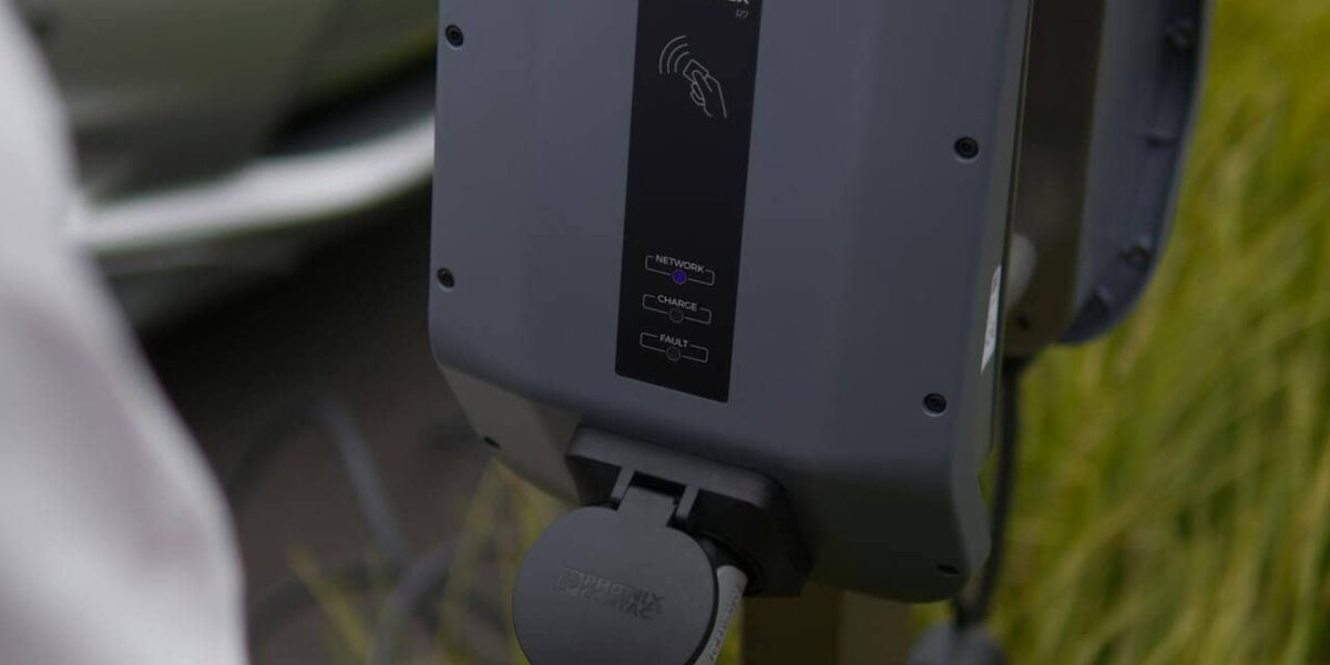 a black car battery charger connected to a car battery in a workshop