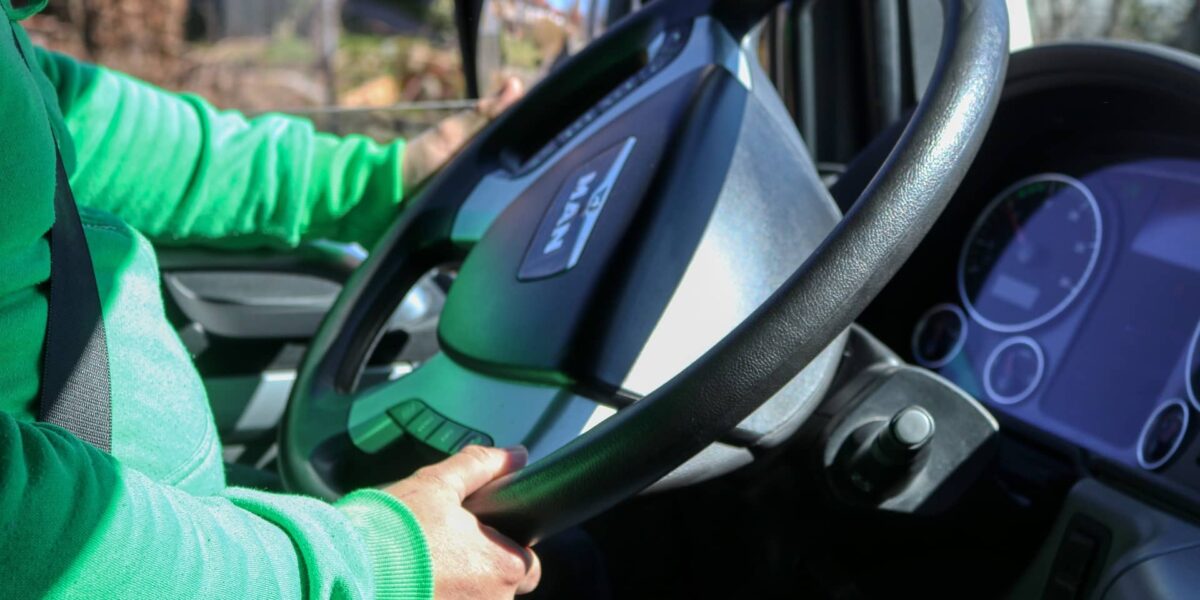 Close-up of a person holding car keys in front of a fleet of business vehicles