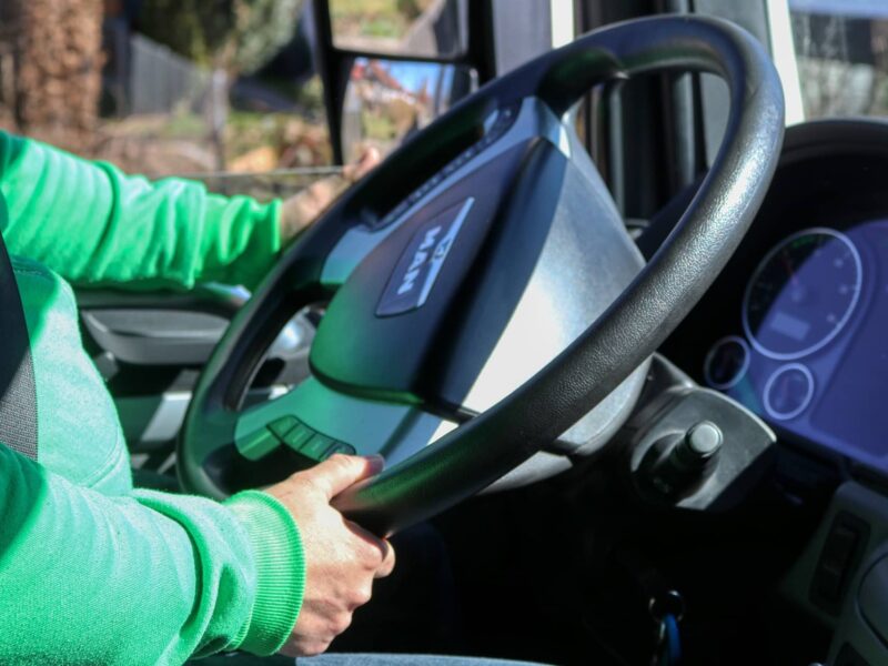 Close-up of a person holding car keys in front of a fleet of business vehicles