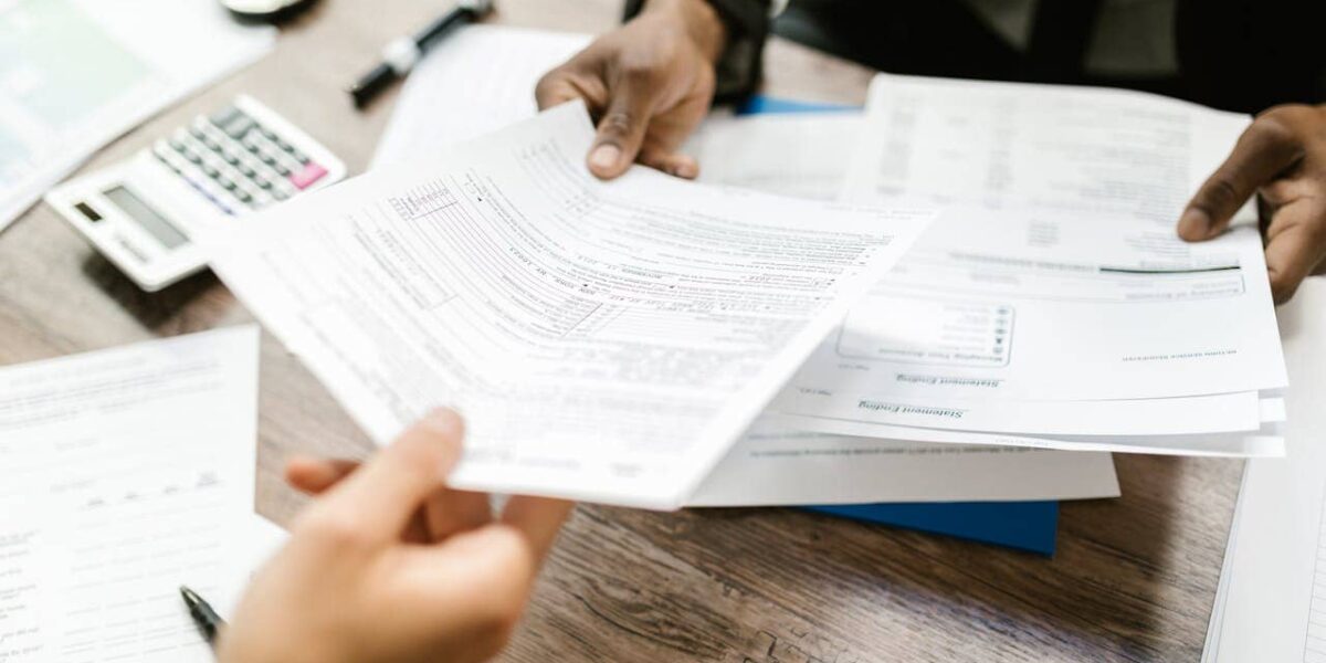 Person comparing car insurance options on laptop and paperwork