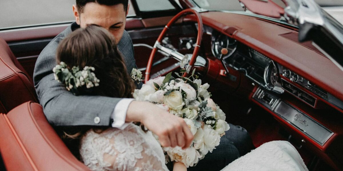 happy couple next to classic wedding car on their big day