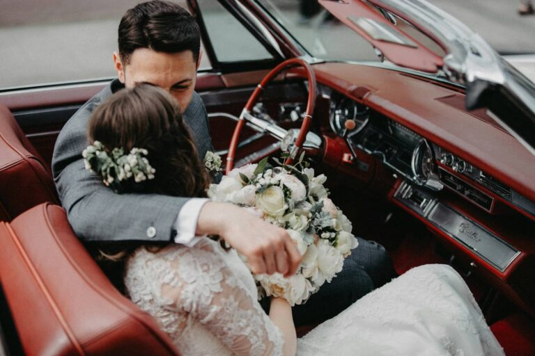 happy couple next to classic wedding car on their big day